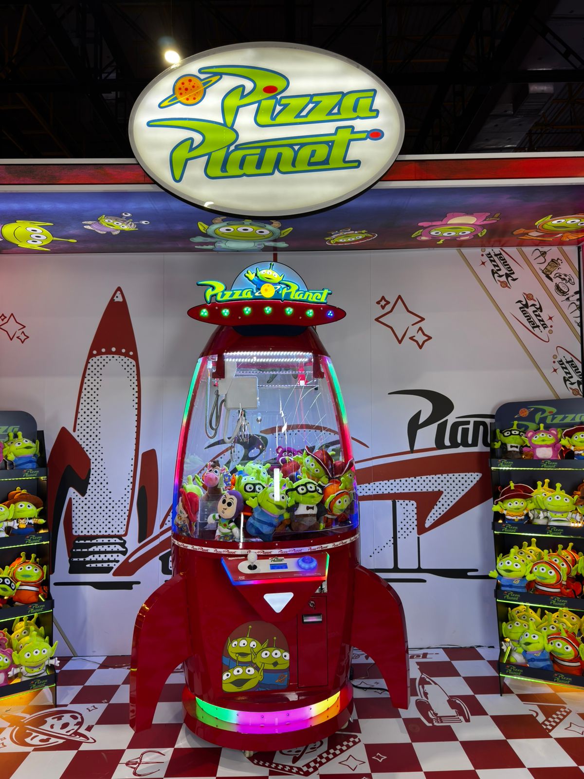 Close da máquina Space Crane Pizza Planet com pelúcias dos aliens de Toy Story na vitrine